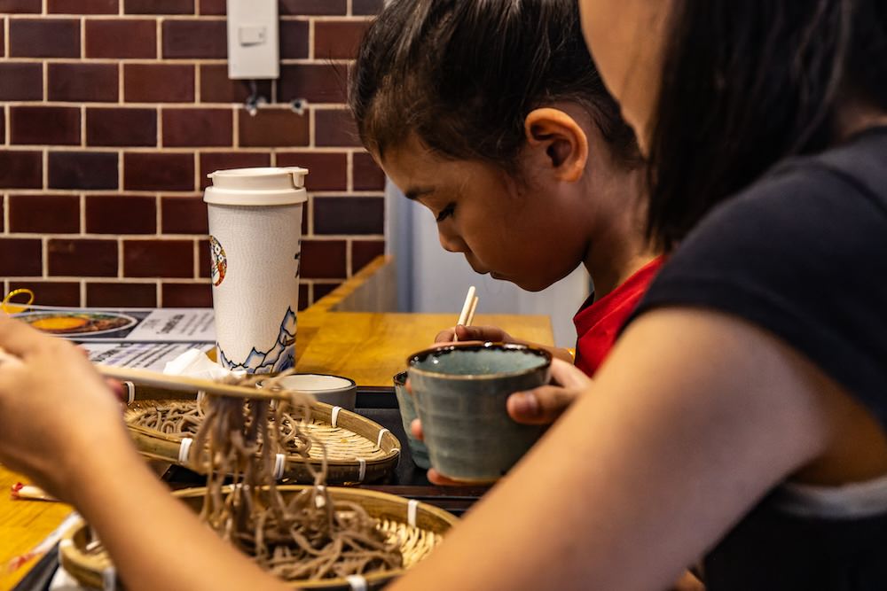 カオサン通りの蕎麦カフェ 中の で十割蕎麦を食べるタイ人