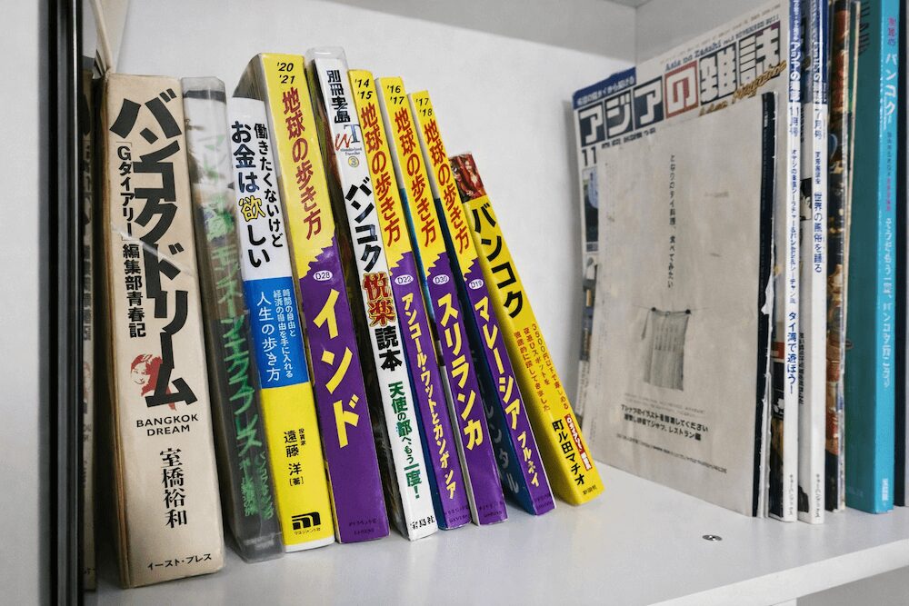 バンコクの日本人専用宿「うらしま館」の本棚に並ぶガイドブック
