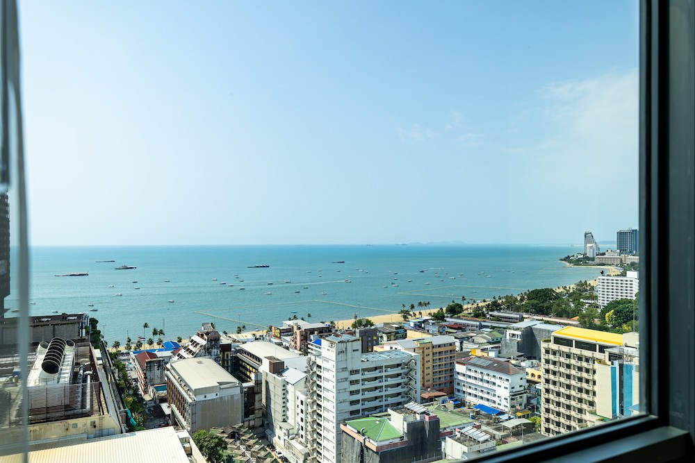 サマセットパタヤの客室「1-Bedroom Premier with Seaview」のベッドルームから望むオーシャンビュー