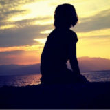 ビーチで夕日を眺めている女性 アイキャッチ画像