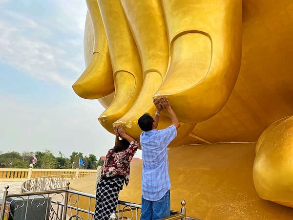 巨大仏像ルアンポーヤイの指に触れる人々
